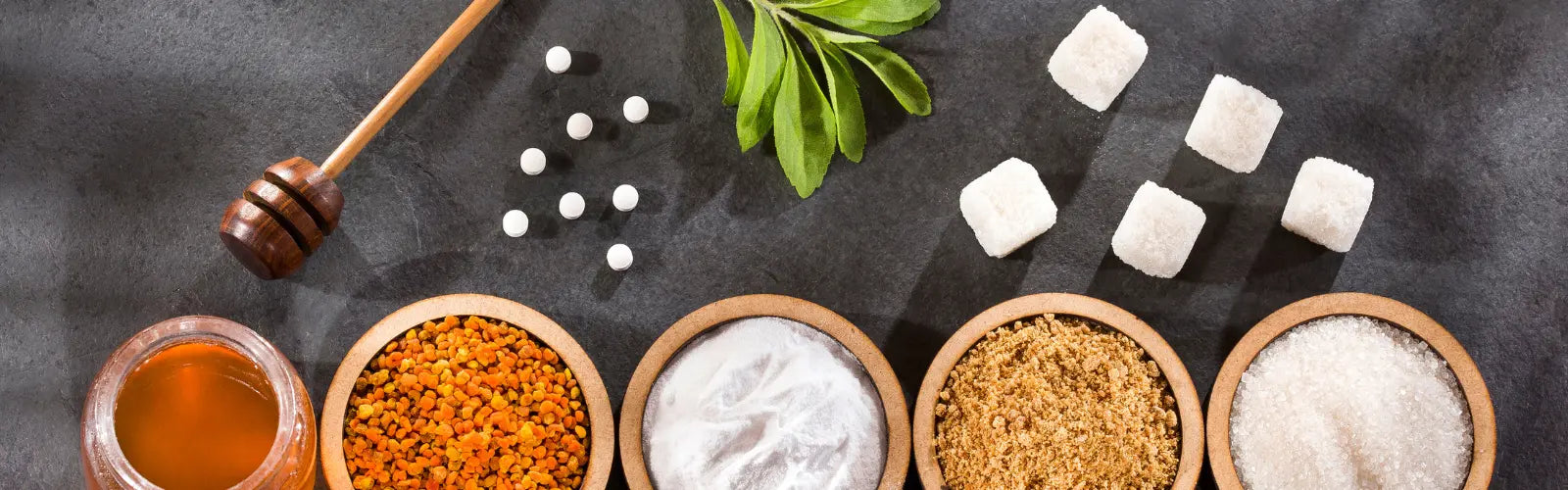 Honig, Süßstoffe, Stevia-Blätter und verschiedene Zuckerarten auf dunkler Oberfläche